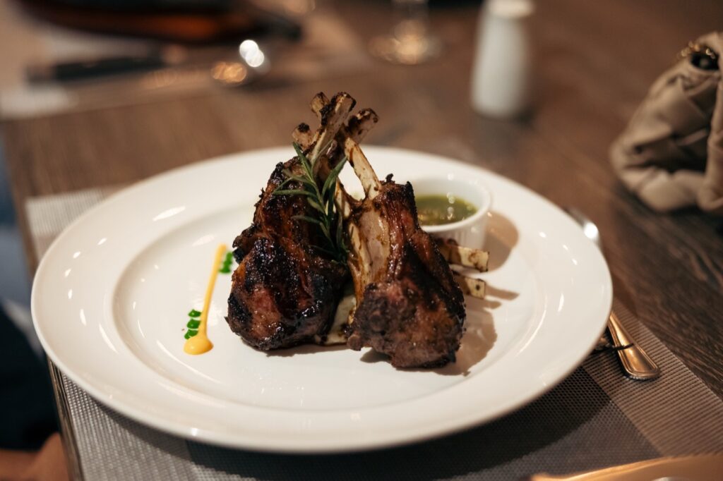 A herb-crusted rack of lamb, carved and plated with chimichurri