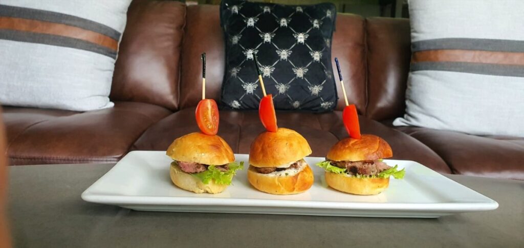 Three steak sliders skewered and served on a white platter