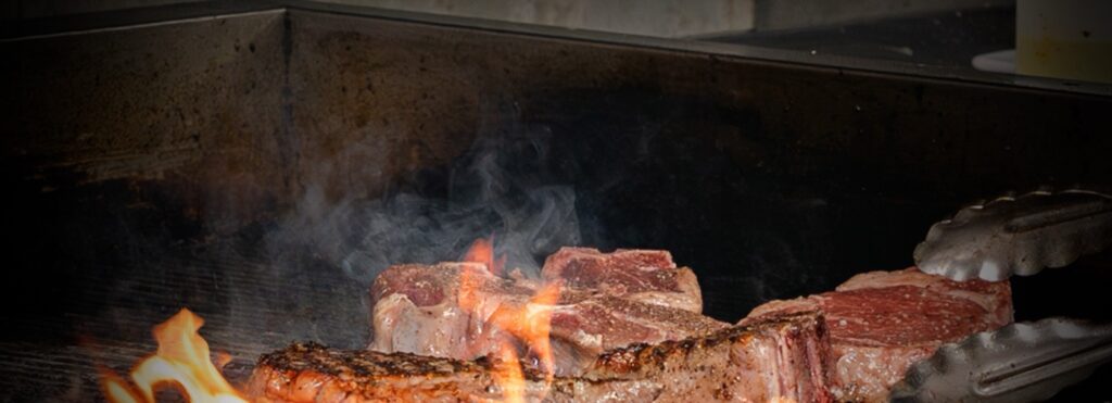 USDA Prime steaks over open flame at The Ivy Steakhouse
