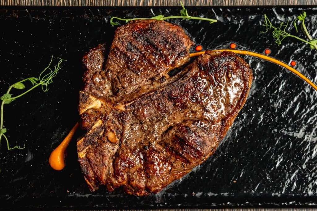 A grilled USDA Prime porterhouse steak on a slate board
