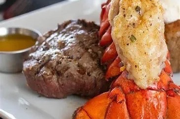 A filet steak served with a lobster tail and drawn butter