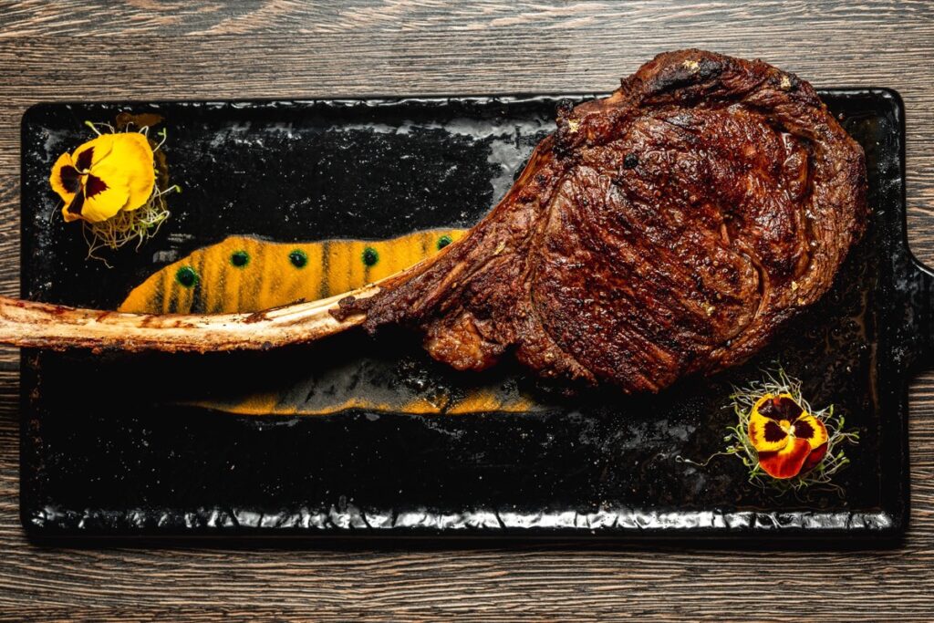 A long-bone USDA Prime tomahawk steak on a slate board