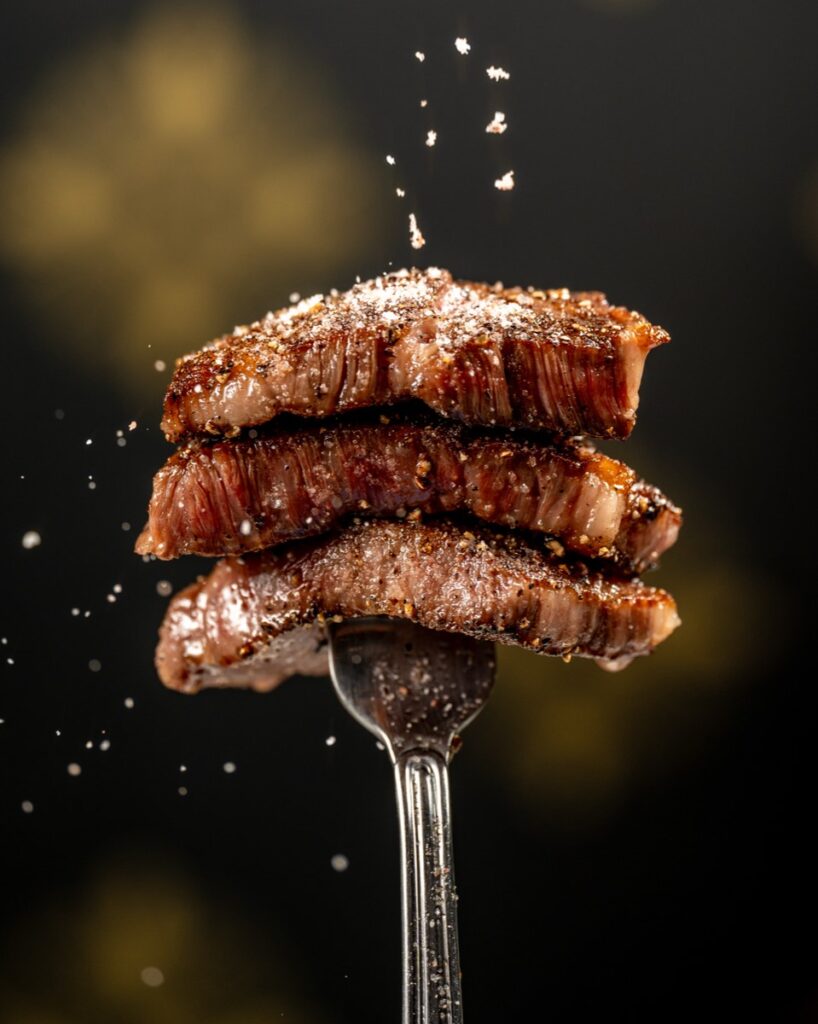 Salt falling over a stack of seared A5 wagyu striploin slices