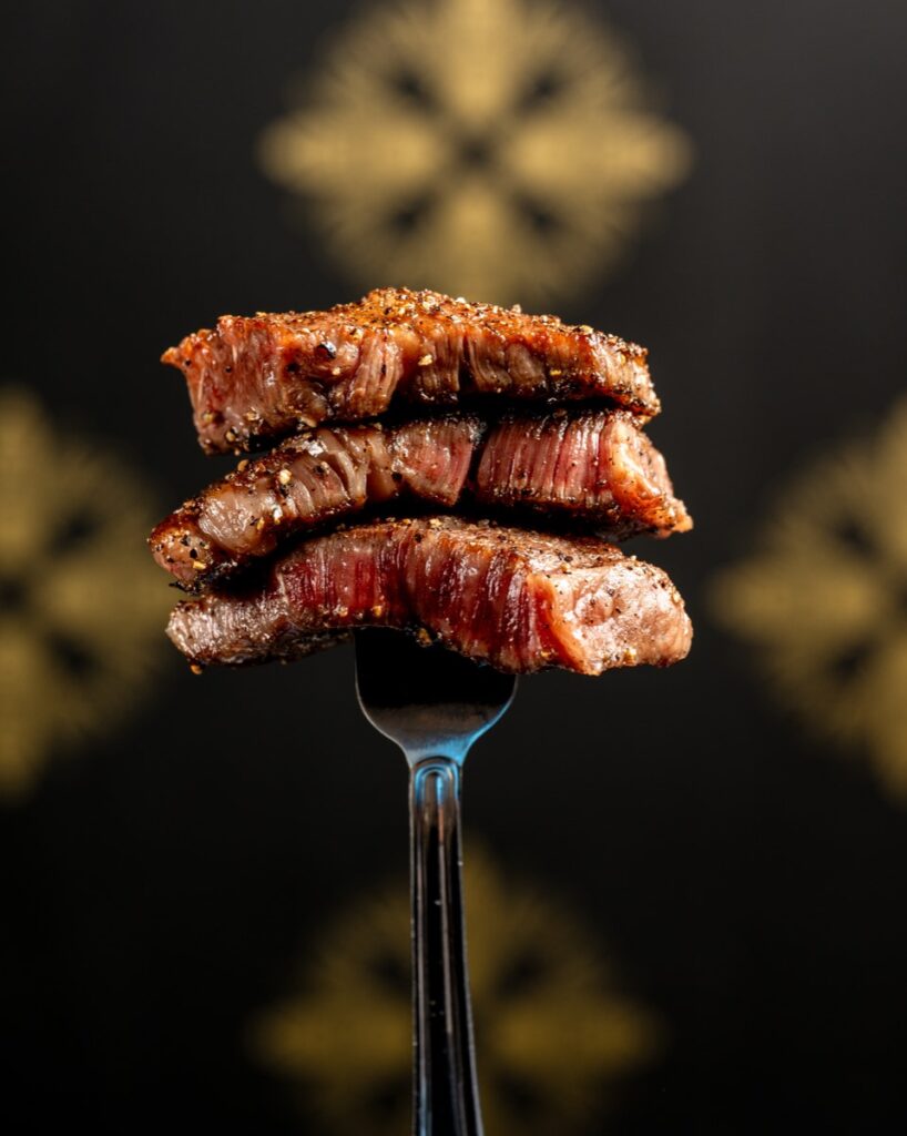 Three seared slices of A5 wagyu stacked on a fork
